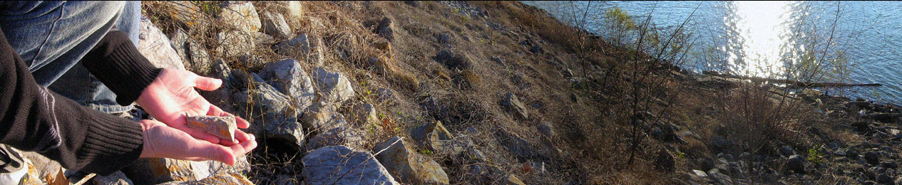 A photograph of Post-K DuMarais holding one of the rocks from the side of a levee in New Orleans next to the Mississippi River